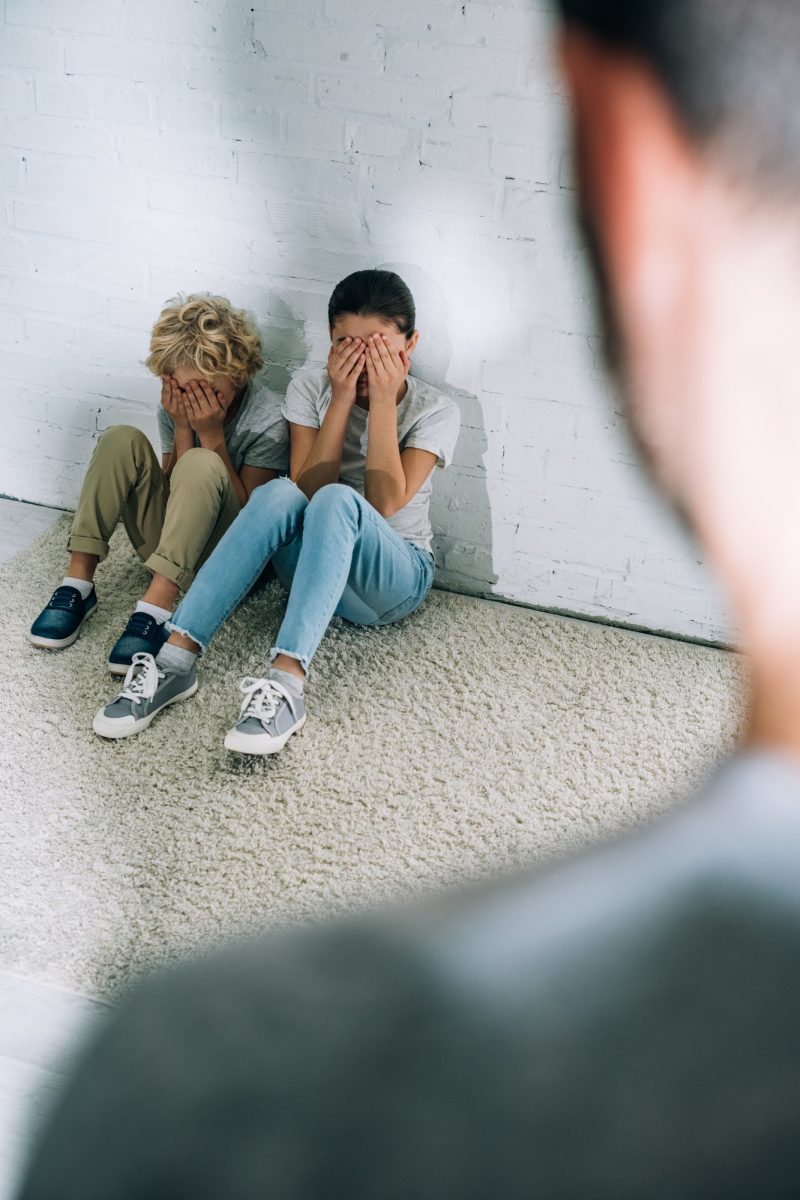 cropped-view-of-father-and-scared-children-sitting-on-carpet.jpg